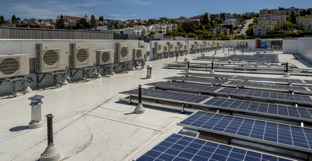 rooftop heat pumps with solar panels in the foreground.